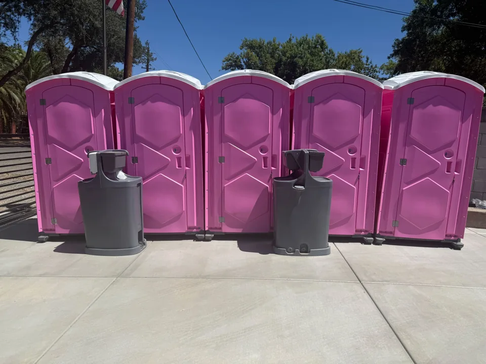 Freestanding handwashing stations in front of portable toilets